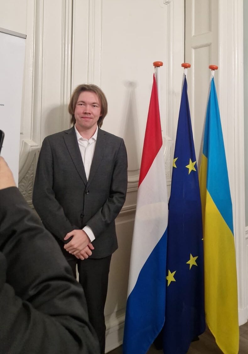 Robin van Schaik standing in front of the Dutch, European and Ukrainian flag. Photo taken inside the Ukrainian embassy to the Kingdom of the Netherlands in 2025.